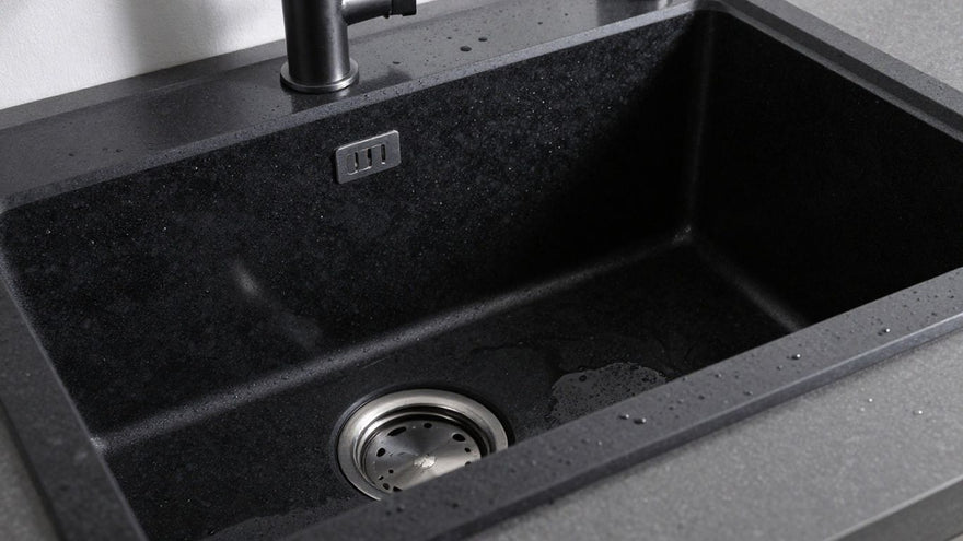 Sleek black granite kitchen sink with water droplets.